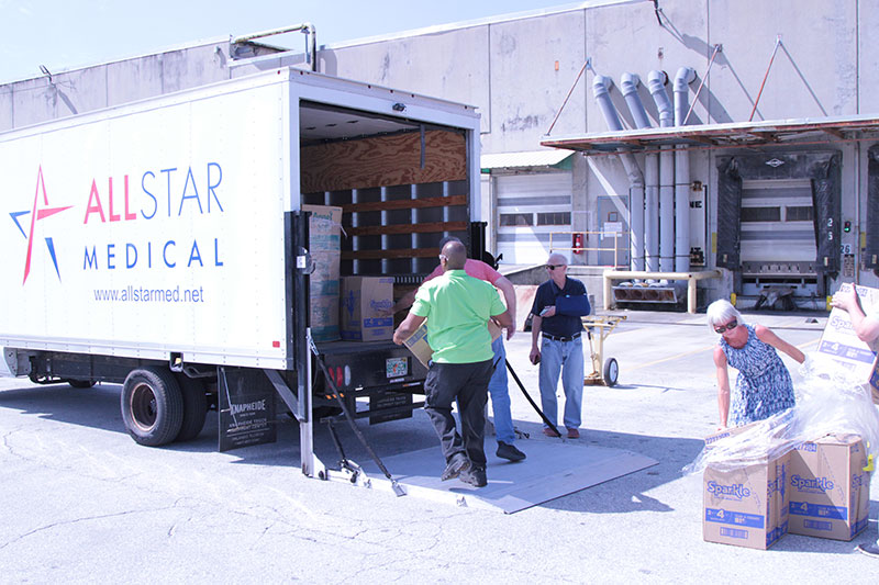 Employees load pallets of paper goods